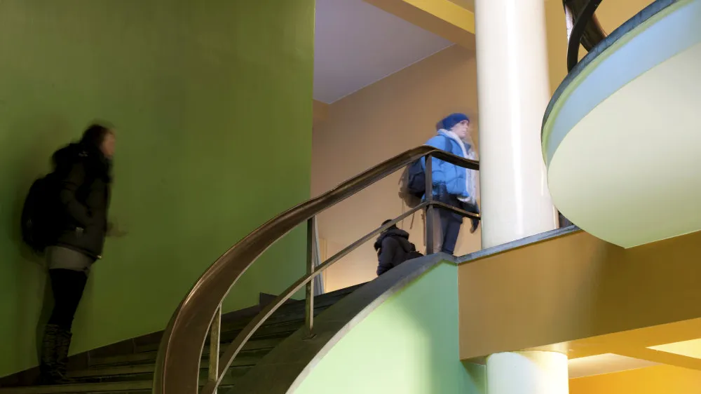 Image of people walking up stairs, green wall