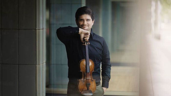 Man smiling, holding violin