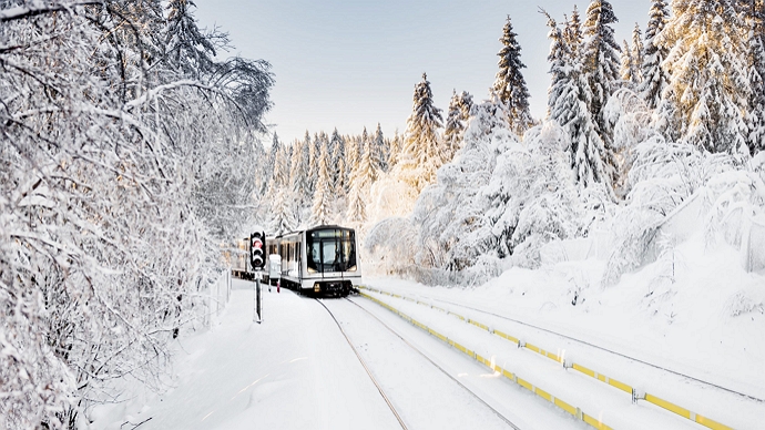 A white Oslo subway on its way up to Frognerseteren on a winter day