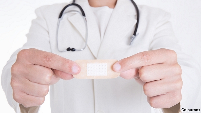 Doctor in white frock holding up a bandaid