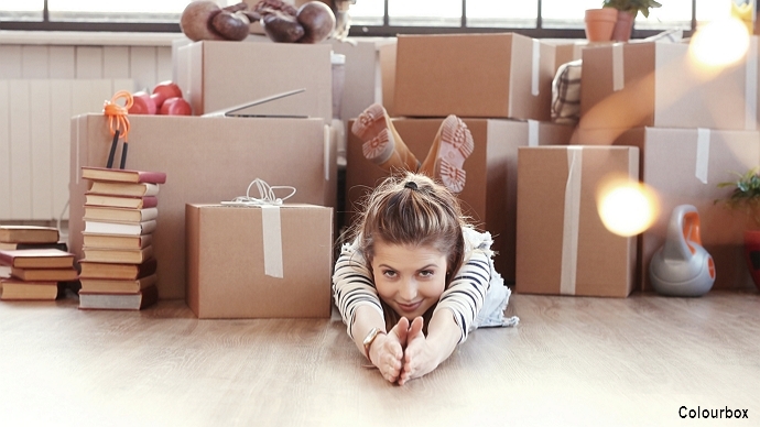 Young woman lying on her stomach in front of cardboard boxes; illustration photo: colourbox.com