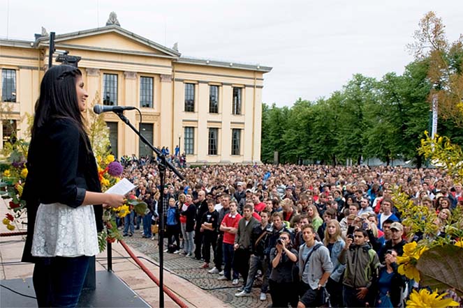 A woman speaking in front of students outside the University Aula