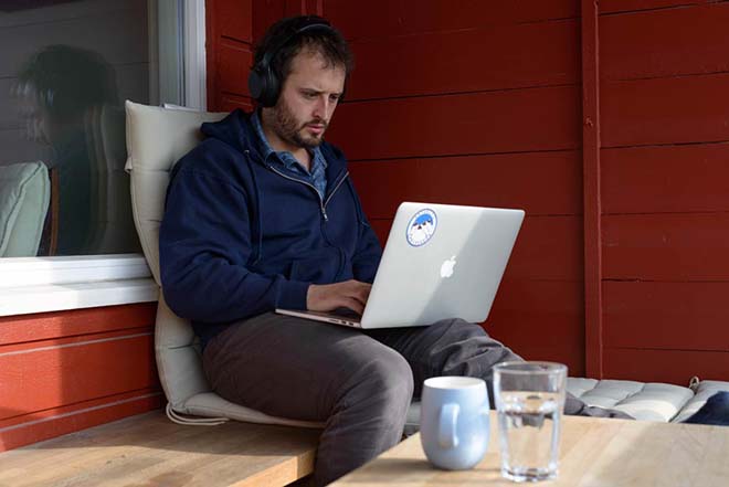 man sitting outside of his house, working on a computer