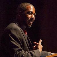 Close-up shot of Dr. Samuel Kelton Roberts speaking, a podium barely visible in the lower right corner.