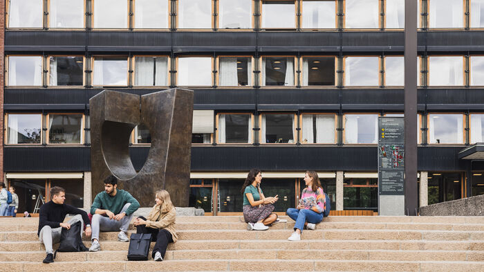 Students sitting on the stairs in front of a building at the university