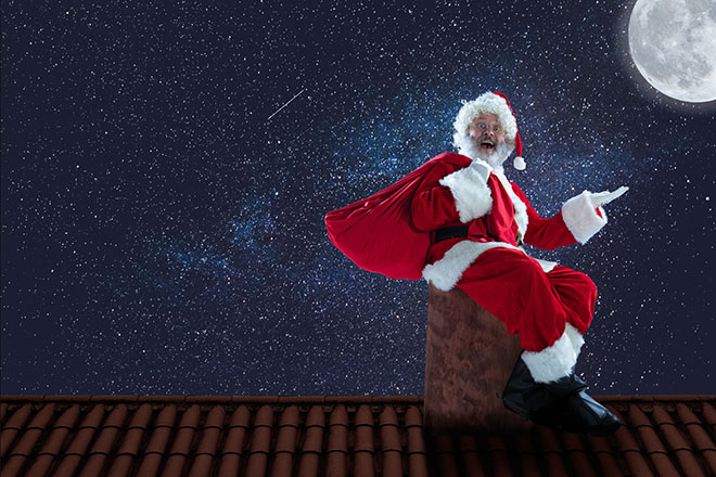 Julenisse som sitter på en pipe med stjernehimmel og måne i bakgrunnen