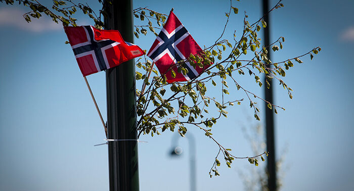Det norske flagget som vaier i vind. Blå himmel.