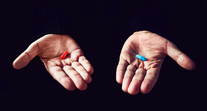 Mørk bakgrunn, to hender med en rød og blå pille i hver hånd.