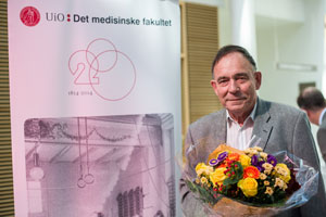 Øyvind Larsen med blomster foran banner med motiv fra 200-årsjubileet.