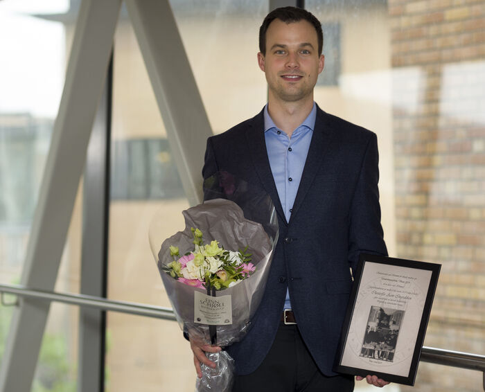 Christoffer Aam Ingvaldsen er vinner av vårens undervisningspris. Her med diplom og blomster på Rikshospitalet like etter utdelingen.