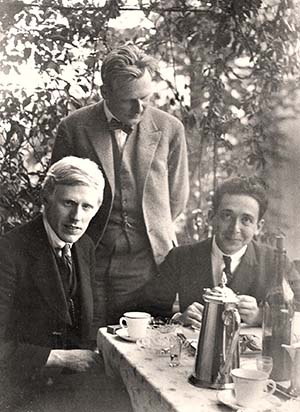Group picture, three men sitting around a table in the garden