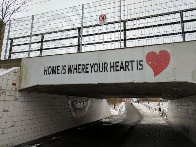 Teksten «Home is where your heart is» står med svart skrift på en bro. Et rødt hjerte ved siden av. Foto.