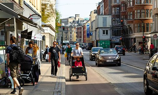 Bilde av gateliv i København med gående, syklende og biler. Foto