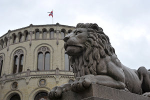 Stortinget i bakgrunnen og en statue av en løve i front.