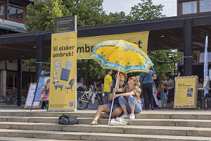 To personer på Fredrikkeplassen som holder en fargerik parasoll