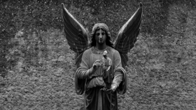 En statue av en engel som holder en liten figur av Athene i hånden.  