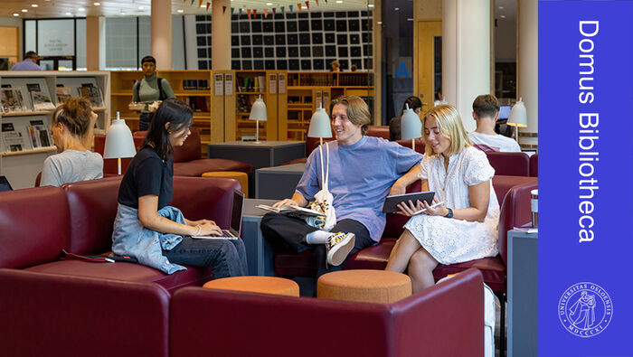 Studenter i rød sofa på Universitetsbiblioteket
