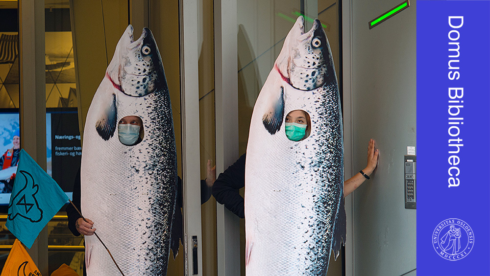 To klimaaktivister i fiskekostymer foran en dør