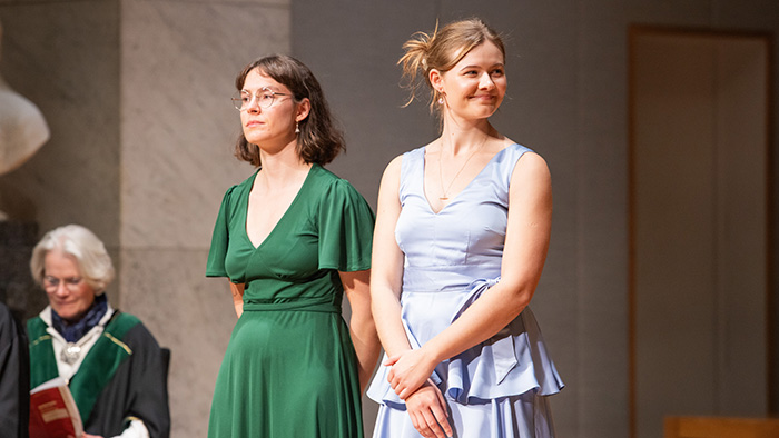To mottakere av bærekraftsprisen i fine kjoler står og smiler på scenen