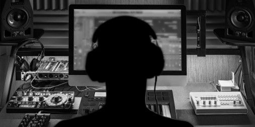 Backhead of a person with headphones and who is looking at a PC. Photo.
