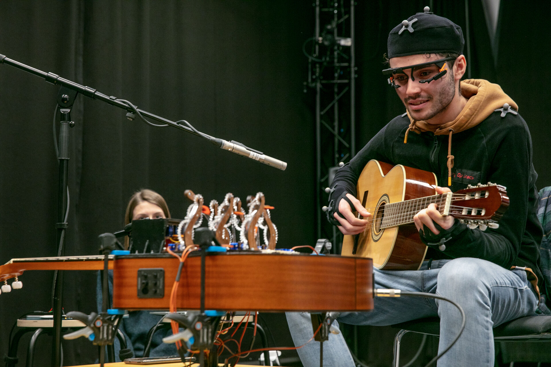 A human guitarist with eye-tracking glasses and motion-capture suit improvising a duet with Professor Plucky as part of a user study.