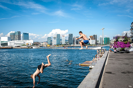 To unge menn hopper fra brygga på Sørenga i Oslo.