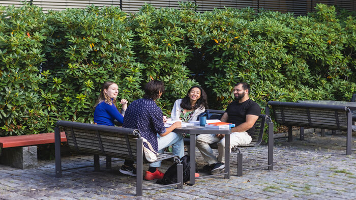 Fire studenter sitter ved et bord ute. Foto