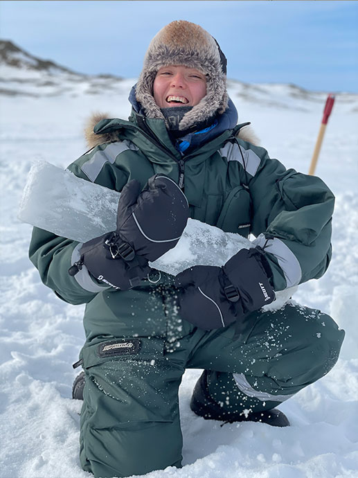Portrett av studenten Celine på Svalbard i vinterdress og med isblokk i hånda