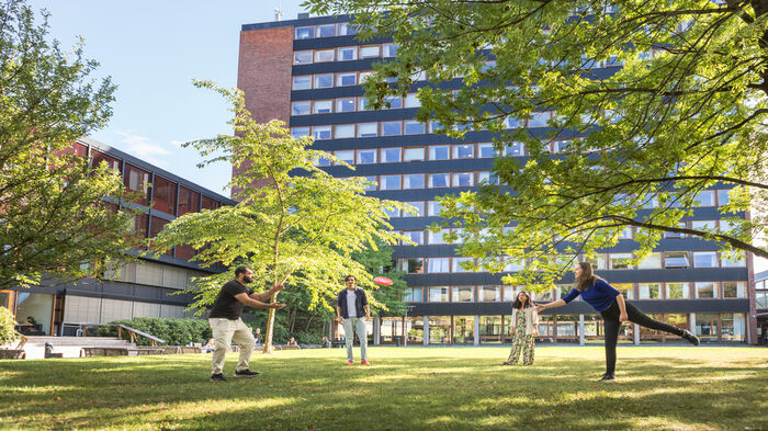 En gruppe studenter som kaster frisbee på plenen bak Niels Treschows hus.