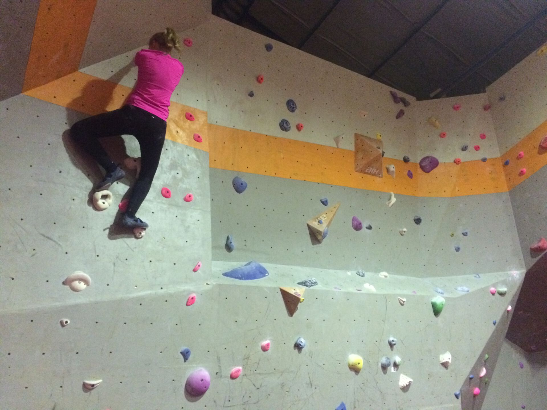 Jente som klatrer i en buldrevegg