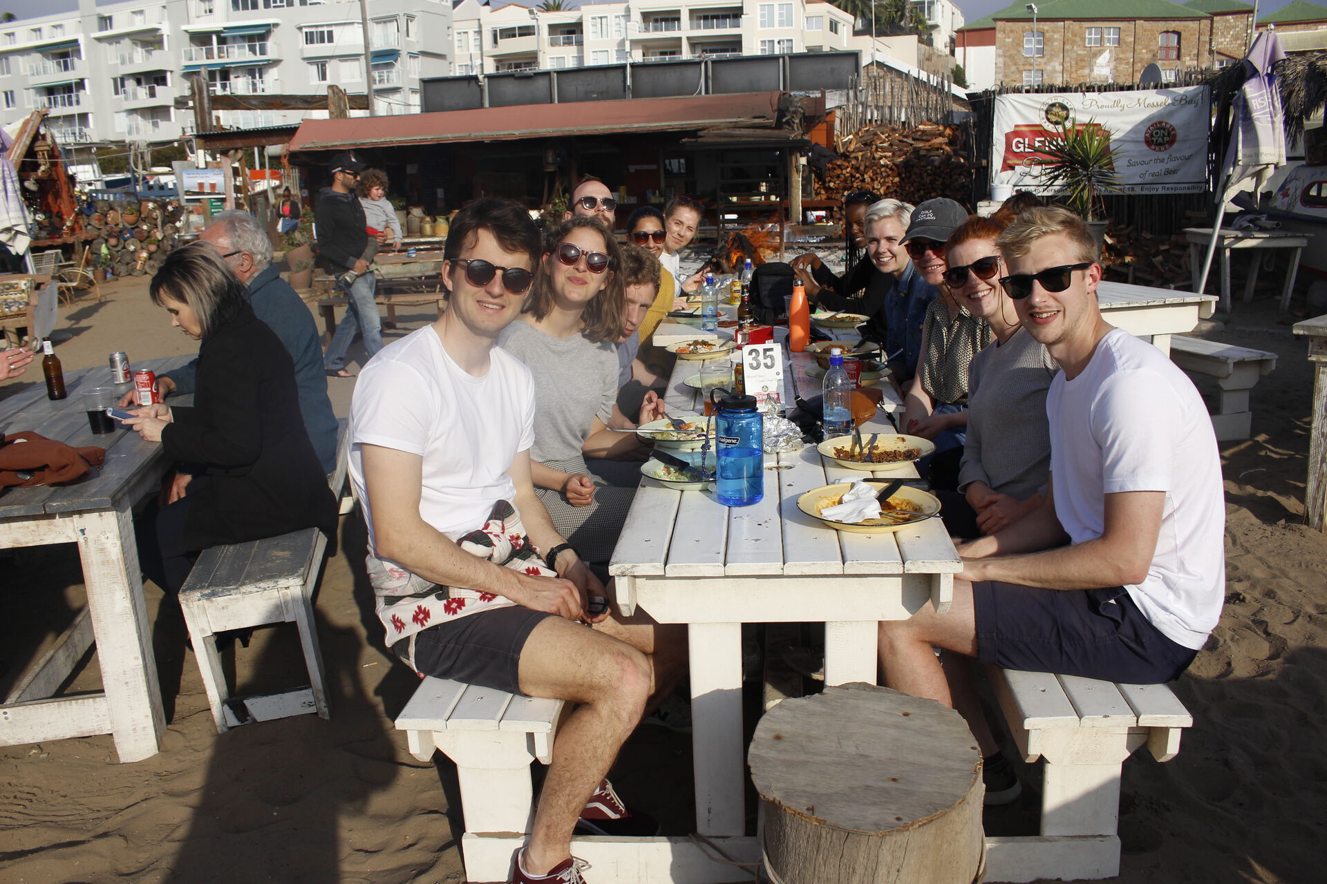 Flere studneter som sitter samlet rundt et bord på en uteservering i Cape Town og spiser