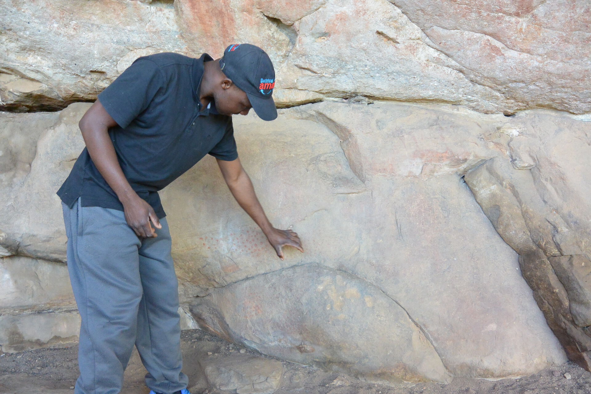 Mann som viser hulemalinger på en fjellvegg