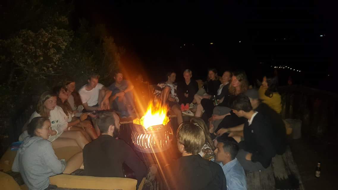 Et titals mennesker samlet rundt et bål i mørket