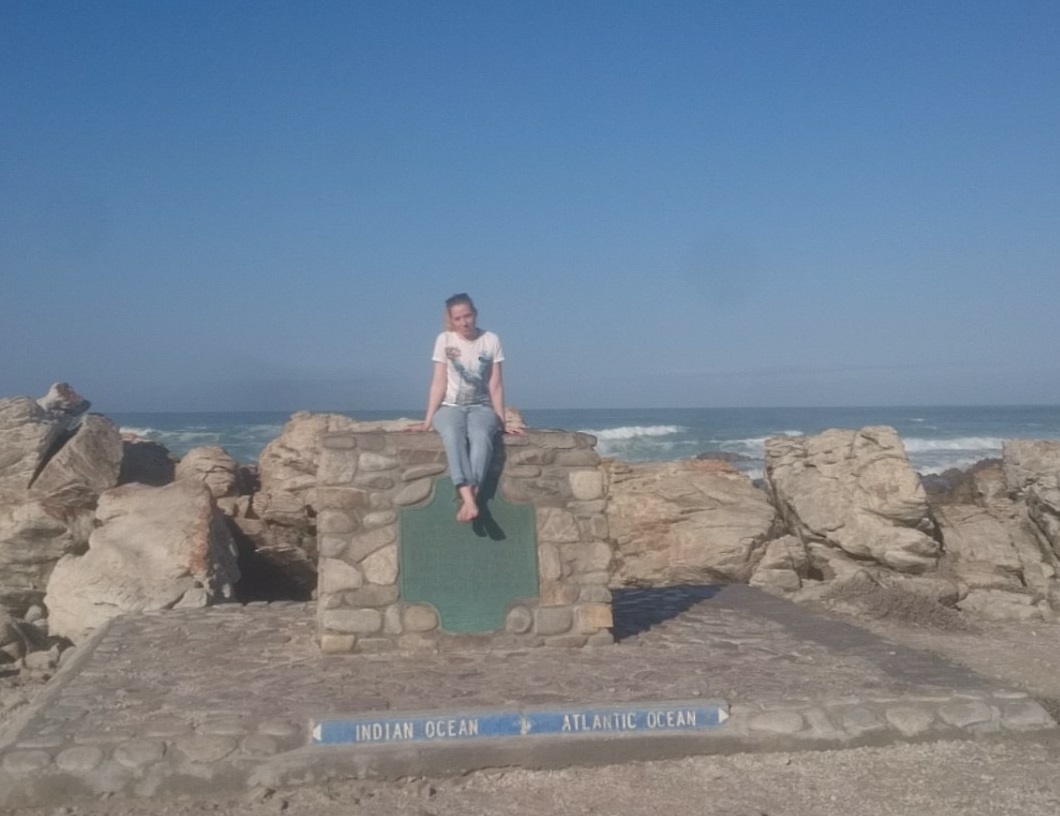 Jente som sitter på en sten ved havet i Cape Town