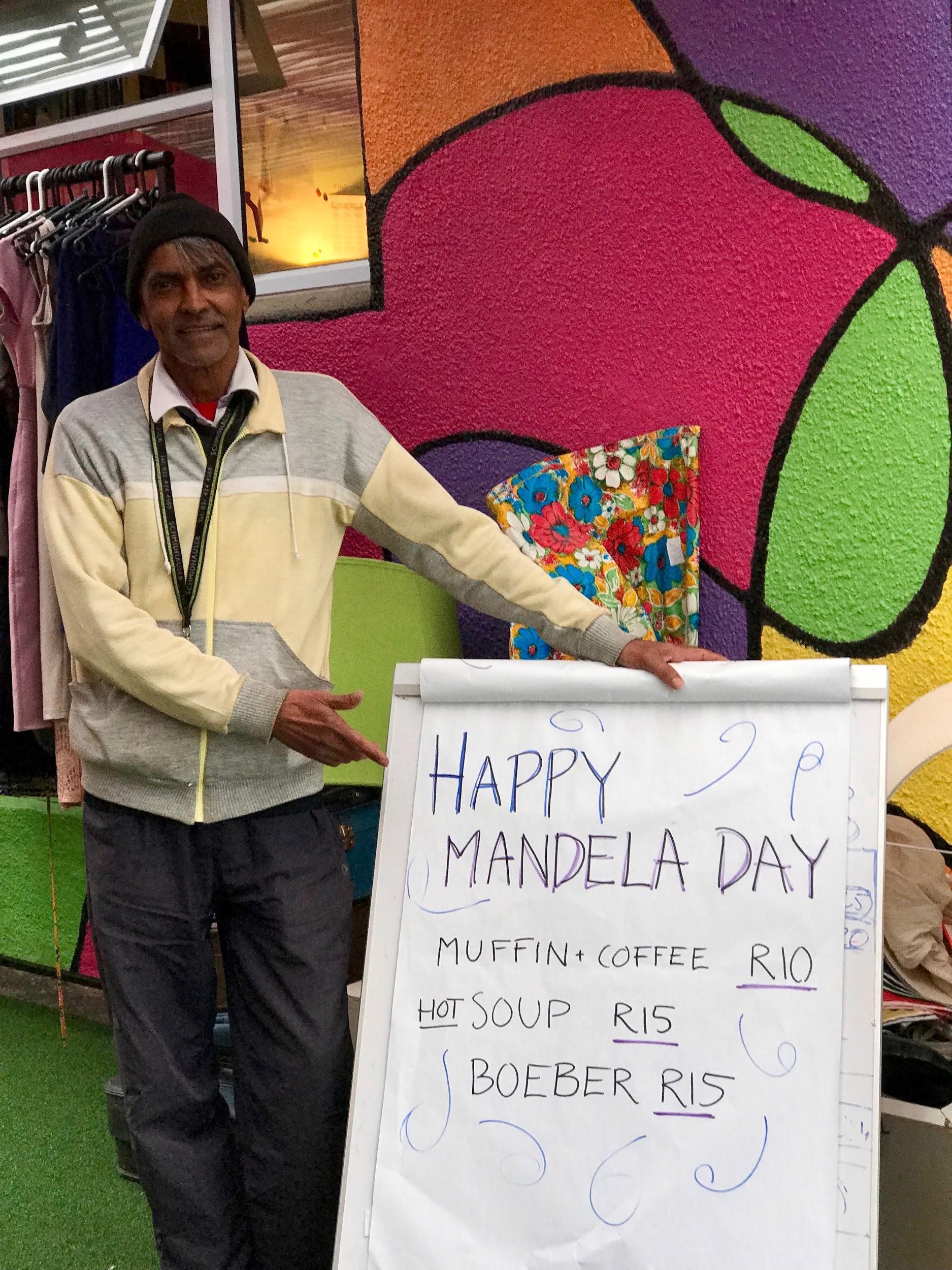 En beboer på NOAH viser frem et skilt om at det er Mandela Day.