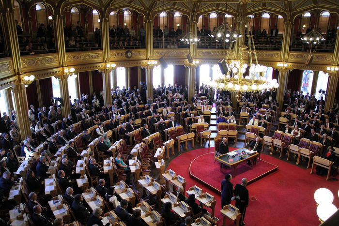 Bildet kan inneholde: stol, tilbehør til musikkinstrumenter, hall, dress, bord.