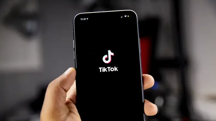 Bilde av en hånd som holder en telefon med tiktok-logoen på skjermen
